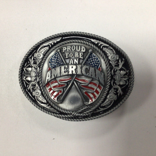 An oval metal belt buckle featuring a patriotic design with crossed axes and American flags, surrounded by the engraved text 'PROUD TO BE AN AMERICAN'.